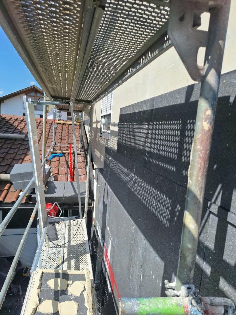 Schwarze Dämmplatten werden an einer Fassade angesetzt